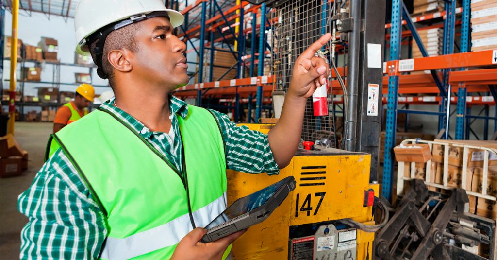 Warehouse worker inspecting stocks while holding a Getac rugged tablet.