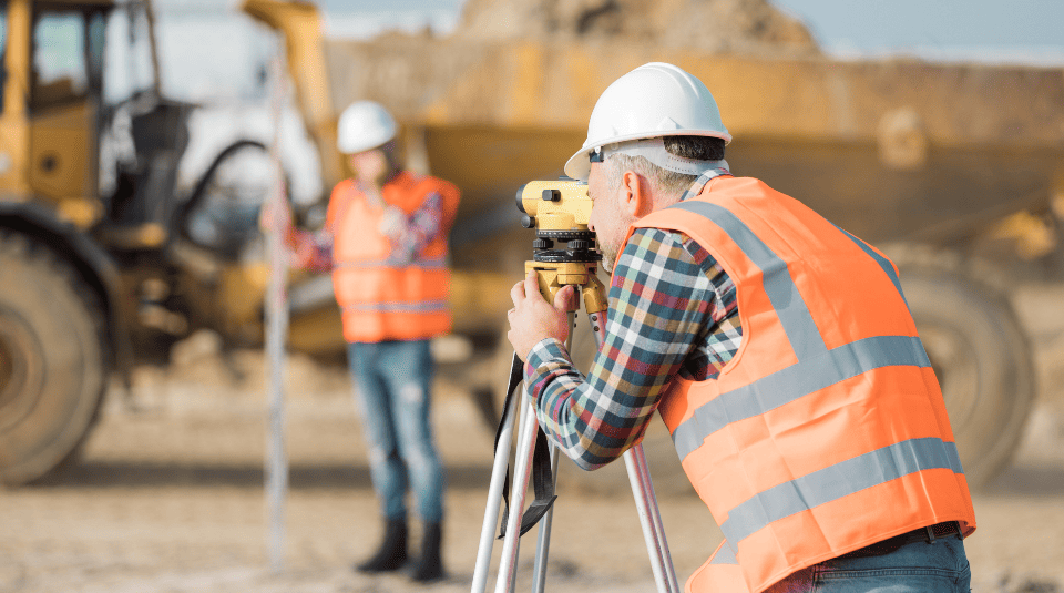 Two road construction workers using measuring device on the field