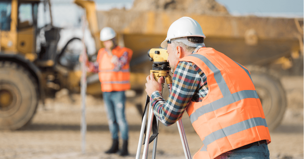 Two road construction workers using measuring device on the field