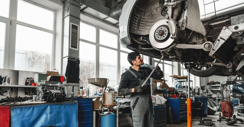 Vehicle technician working on wheel alignment on a car.