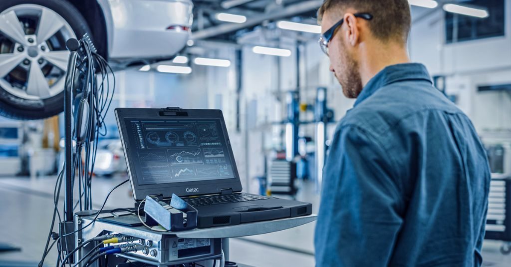 automotive technician working with rugged laptop at the workshop