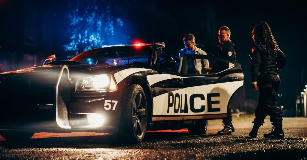 police officers guiding a person into a police car