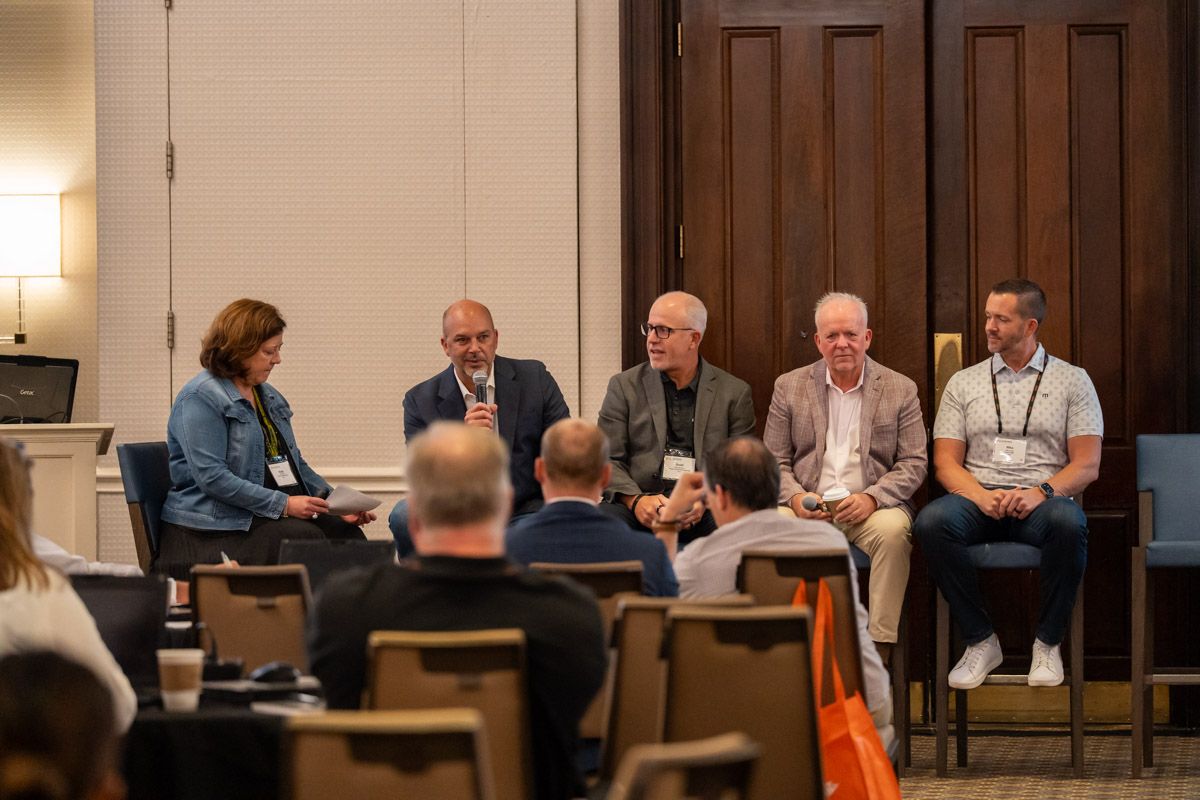 Panel discussion at a conference, with the speakers speaking into microphones as attendees watch, illustrating Getac’s partner program and channel collaboration.