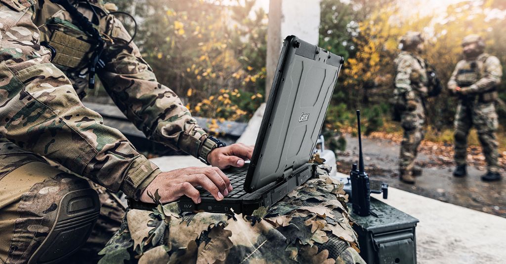 military personnel using a rugged laptop while out in the field