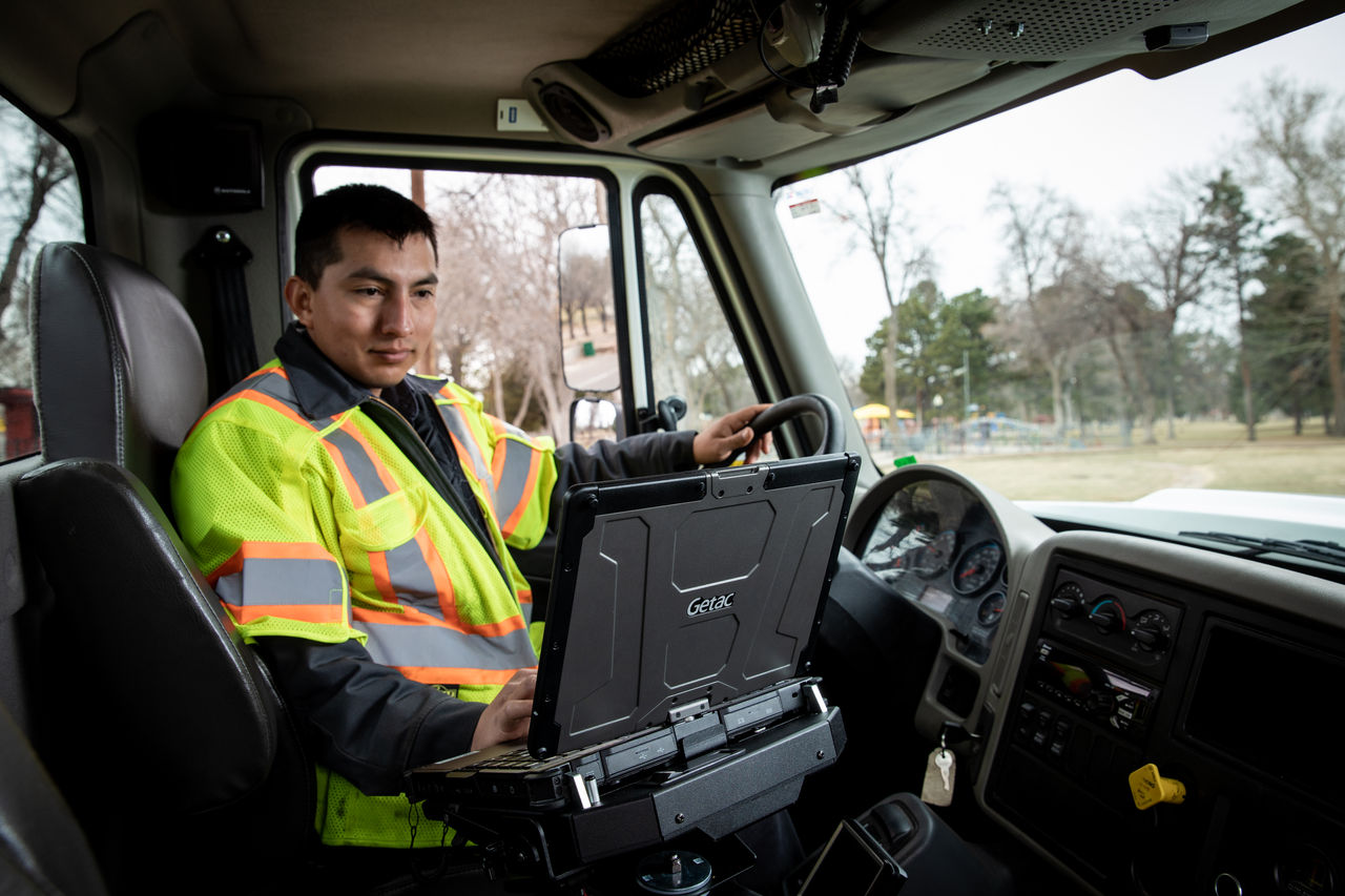 A utility worker uses a Getac rugged laptop secured in a vehicle docking station, highlighting the importance of reliable in-vehicle docks for safe, efficient utility fleet operations.