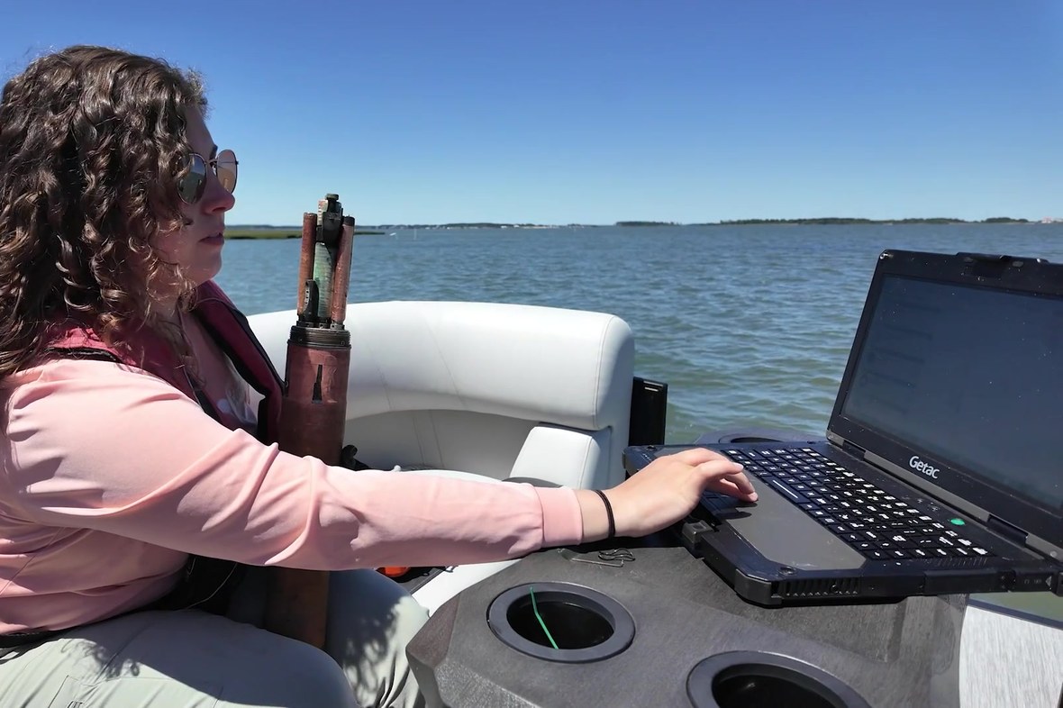 Inland Bays scientist typing on a Getac B360 rugged laptop aboard a boat on open water