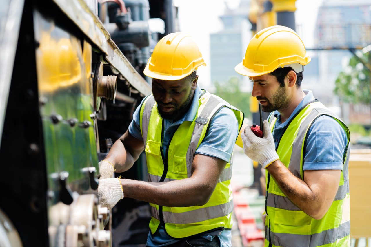 Telecom technicians using a Getac B360-fully-rugged laptop to inspect network infrastructure equipment in a field deployment environment